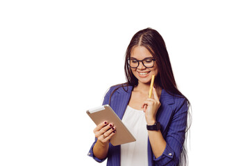 Fototapeta premium Adorable brunette in glasses with long hair dressed in dark blue suit cute smiling, holding tablet, looks happy, makes video call, over transparent background with copy space. People sincere emotions