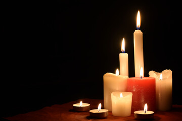Burning candles on table on black background indoors. Concept of mourn, grief or mourning. Memorial Day. Copy space