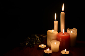 Burning candles on table on black background indoors. Concept of mourn, grief or mourning. Memorial Day. Copy space