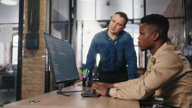 Black And Caucasian Male IT-Specialist Working Together Of Project In Office, Co-Workers Collaborate