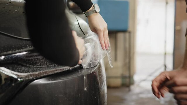 Close up to PPF installation process on a front headlight . PPF is a paint protection film which protect paint from scratches and stone chips. Concept of: guard, protect, car, new, work.