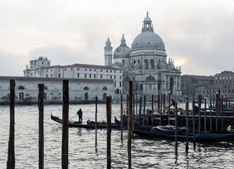 Gondoliers and gondolas, early morning, Venice, Italy. Basilica di Santa Maria della Salute in distance.