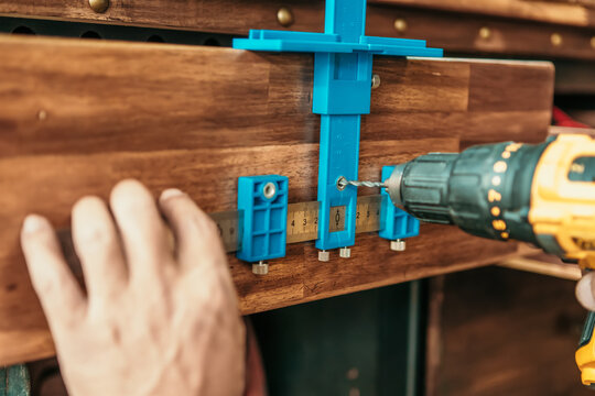 carpenter use a cabinet hardware jig adjustable punch locator drill guide sleeve for Install cabinet handles and knobs ,DIY maker and woodworking concept. selective focus