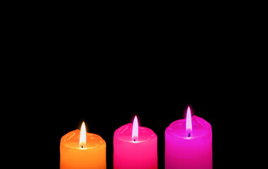 Burning Three of Different Vibrant Colors Candles on Black Backdrop with Copy Space