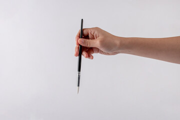 Hand using a little paintbrush isolated on a white background