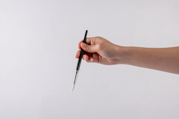 Hand using a little paintbrush isolated on a white background