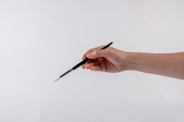 Hand using a little paintbrush isolated on a white background