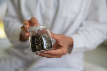 Female scientist in white medical uniform with mock up glass cosmetic jar in hands