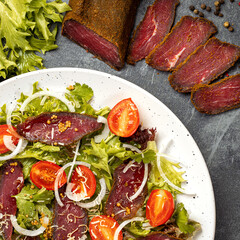 Unusual tasty dish with Dried beef or pork basturma and tomatoes, onion, lettuce, Coriander leaves, cheese.