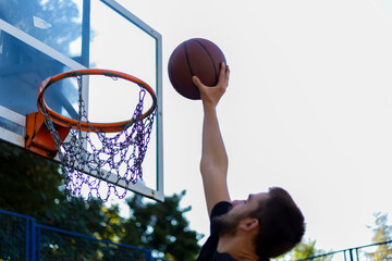 handsome basketball player shooting a ball through the hoop while playing on basketball court...