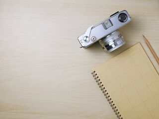 Notebook and camera on wooden texture background