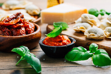 Home cooking - raw tortellini pasta with tomato pesto and sun-dried tomatoes and basil