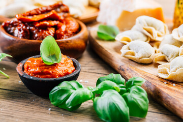 Home cooking - raw tortellini pasta with tomato pesto and sun-dried tomatoes and basil