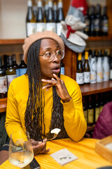 Surprised black woman in the night having dinner with glass of wine