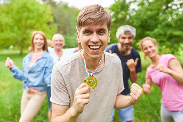 Glücklicher Mann mit Sieger Medaille vor seinem Team