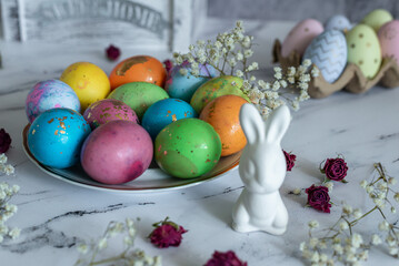 Beautiful multi -colored decorated Easter eggs and a cute white Easter rabbit on a white mromoic background. food composition