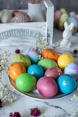 decoration for the holiday, food composition. Beautiful multi -colored decorated Easter eggs and a cute white Easter rabbit on a white mromoic background. Close-up