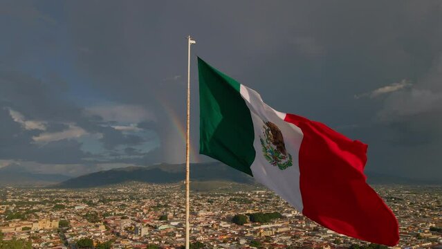 Real Mexican flag waving on a hill in a Mexican city Oaxaca at dramatic sunset.