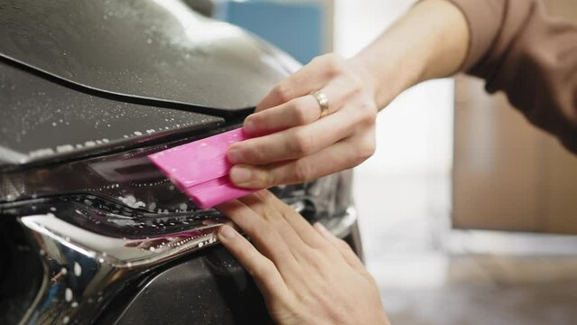 Close up to PPF installation process on a front headlight . PPF is a paint protection film which protect paint from scratches and stone chips. Concept of: guard, protect, car, new, work