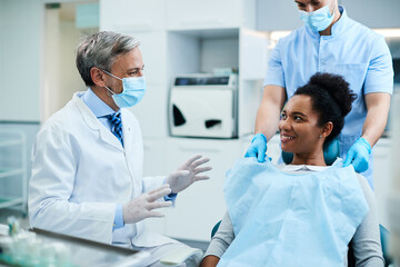Happy black woman communicating with her dentist during appointment at dental clinic.