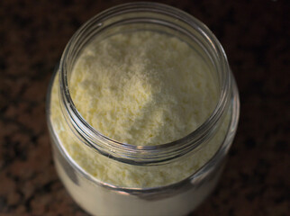 Glass container full of powdered milk. Natural light.