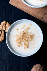 Homemade custard with walnut, Turkish dessert muhallebi on a wooden background. Homemade custard with walnut. 