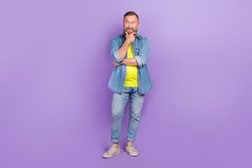 Full length photo of handsome granddad minded look empty space interested wear trendy jeans outfit isolated on yellow color background © deagreez