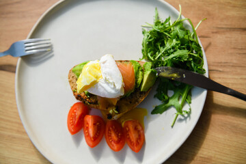Avocado toast with poached egg on a wooden board.