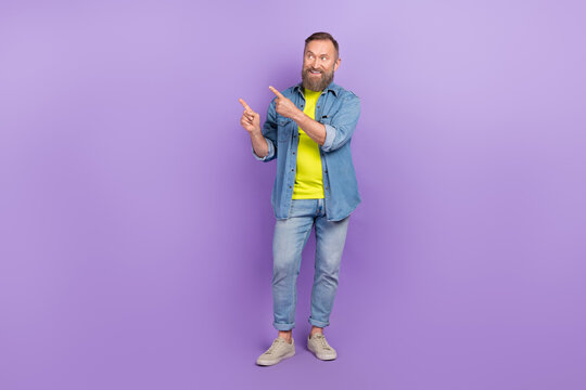 Full body photo of attractive grandpa look point empty shopping advert space wear trendy jeans outfit isolated on yellow color background