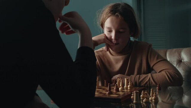 Middle shot of son and his mother connecting through a game of chess. Woman thinks and then makes a move