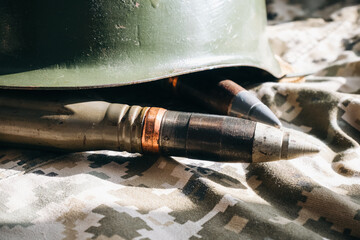 Bullets and helmet on khaki camouflage background. Lend-Lease and Army concept. Sales of weapons and ammunition. Military industry, war, global arms trade.