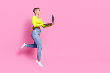 Full size profile photo of attractive active girl jumping run use netbook empty space isolated on pink color background