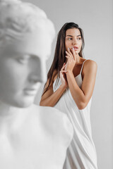 Portrait of young beautiful woman standing near gypsum sculpture Venus face © Oleksandr Kozak
