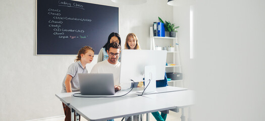 Elementary school teacher leading a coding lesson in a classroom, using a computer to show his students how to code © Jacob Lund