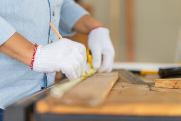 Carpenter working with equipment on wooden table in wood workshop, man doing woodwork in carpentry shop