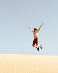Fototapeta na wymiar Single man jump on sand in the Namib desert at sunrise on blue sky background. Travel concept