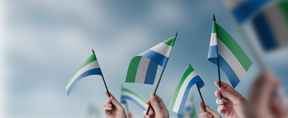 Fototapeta na wymiar A group of people holding small flags of the Sierra Leone in their hands