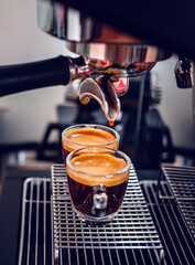 Fototapeta na wymiar Professional espresso machine while preparing two espressos shot in a coffee shop. Close-up of espresso pouring from the coffee machine