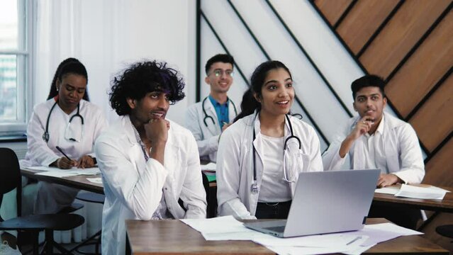 Young multiethnic diverse indian students friends colleagues studying at medical training course at medical university, listening to lecturer professor doctor, participating in discussion healthcare