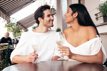 Smiling beautiful woman and her handsome boyfriend. Happy cheerful family. Sexy couple cheering with glasses of red wine at their date in restaurant. Drinking alcohol at veranda cafe