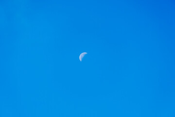 portrait format image of a distant half moon.