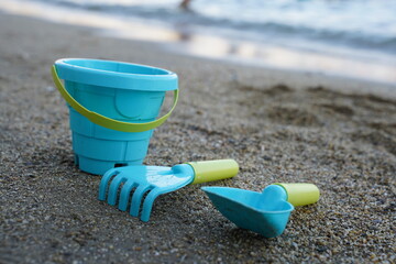 Children's beach toys, bucket, shovel and rake on the sand on a sunny day. The concept of summer holidays with children.