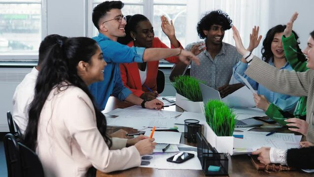 Diverse multiracial multiethnic young students joining hands give high five in air celebrating corporate unity success at office class. International classmates celebrate friendship. United colleagues