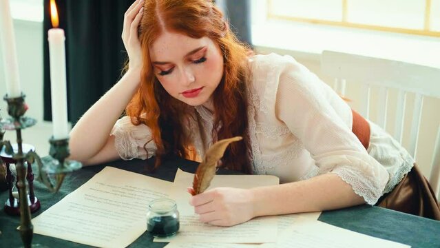 Redhead Girl fantasy princess sits at desk writes letter on sheet paper. woman writer holds pen feather quill in hands close-up works signs documents. Beauty face red lirs long hair. Vintage old book