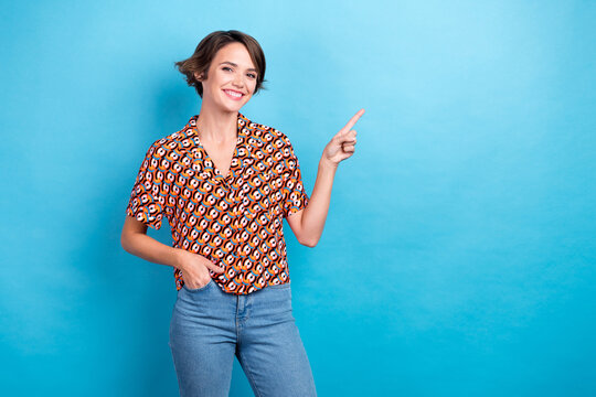 Photo of nice cheerful girl toothy smile direct finger empty space offer isolated on blue color background