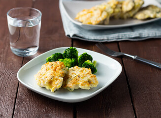 Chicken cutlets with broccoli on a white plate. Brown background.