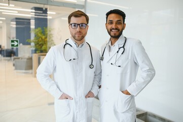 An Indian doctor and a European doctor stand together in a hospital lobby.