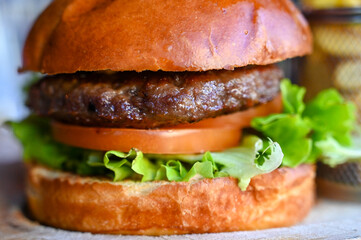 Delicious burger on wood table in restaurant. Tasty hamburger with French fries. Beef burger with fresh salad ingredients served on wooden plate.
