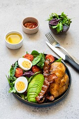 Plate with baked chicken fillet with bacon, fresh vegetables, salad. Popular keto diet, concept of healthy body, food.