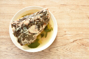 boiled Asian Redtail catfish head with chili and lemon dressings celery tom yum soup on plate
